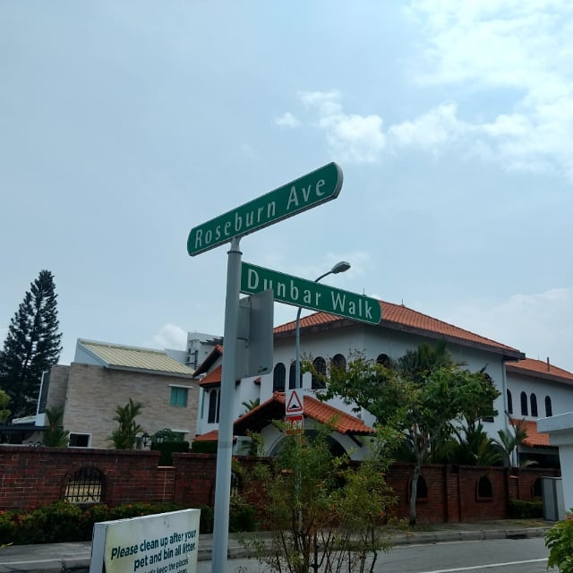 A couple of street signs in a Singaporean neighbourhood, with one saying "Dunbar Walk" and the other saying "Roseburn Avenue".